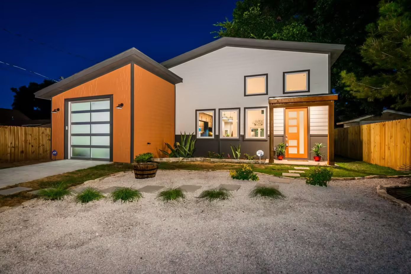 Modern suburban home at dusk with warm lighting and landscaped garden.