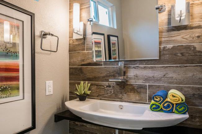 Modern bathroom with rustic wooden accent wall and white basin sink.
