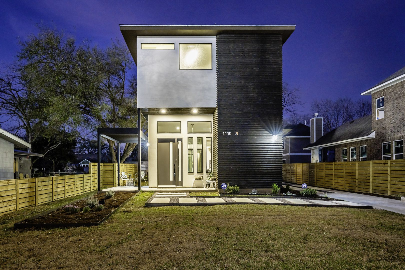 Modern two-story home with evening lighting and a landscaped front yard.